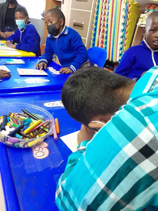 Children taking part in classroom activities at Anne-Stine, with learning materials on blue tables.