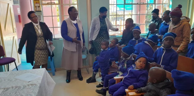 Visitors and children gathered together in the classroom.